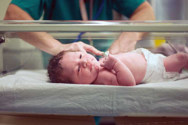 Midwife checking health of newborn baby | Image
