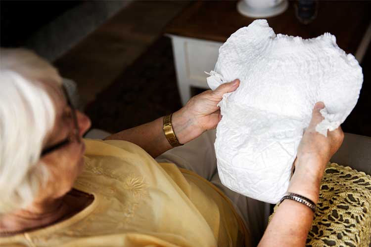 Elderly woman holding incontinence product | Image