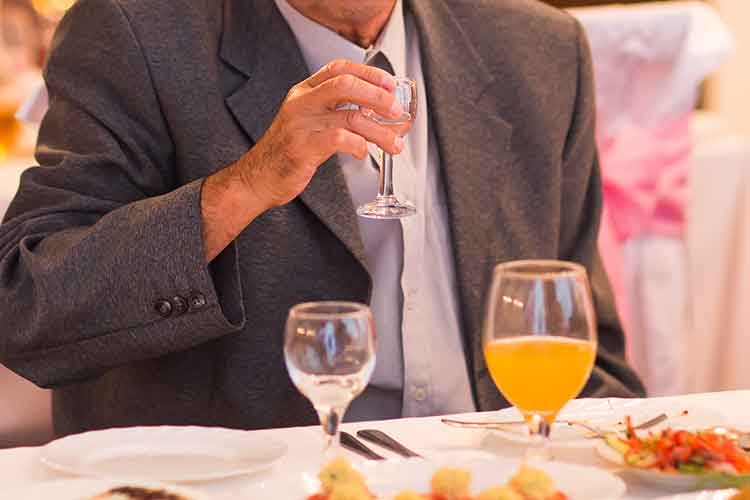 older man sitting at a dining table setting | Image