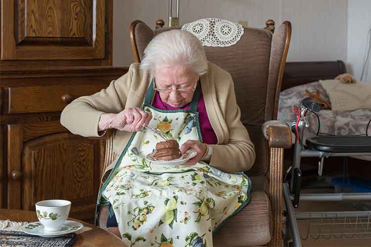 older woman eating food | Image