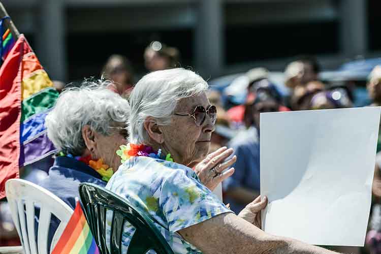 Older couple sitting outside holding a sign