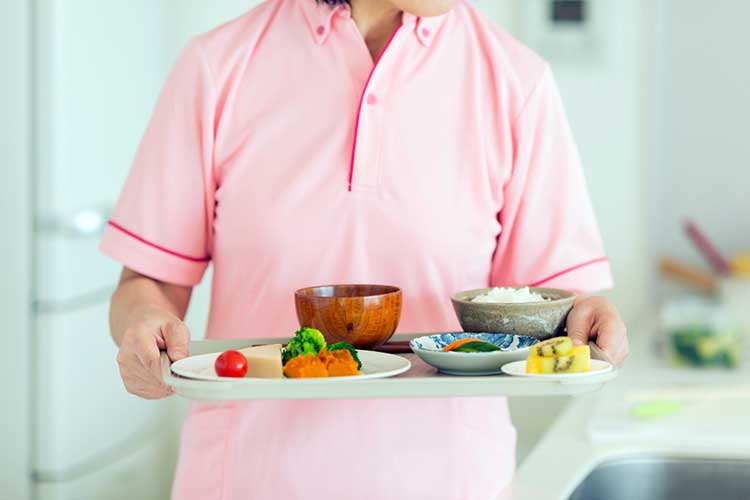 meal planning aged care woman holding tray of food for aged care resident