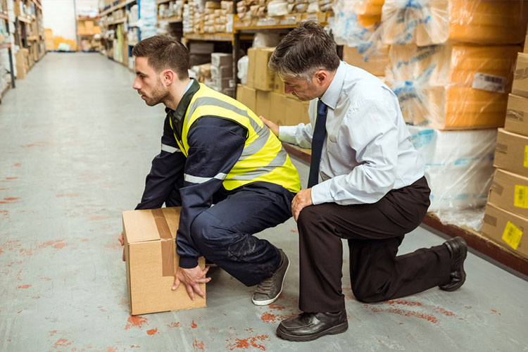 il datore di lavoro mostra la tecnica di manipolazione manuale sicura dei dipendenti per prevenire o limitare il rischio di lesioni