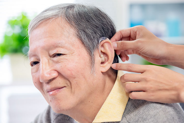 old man with deafness is having hearing aid fitted