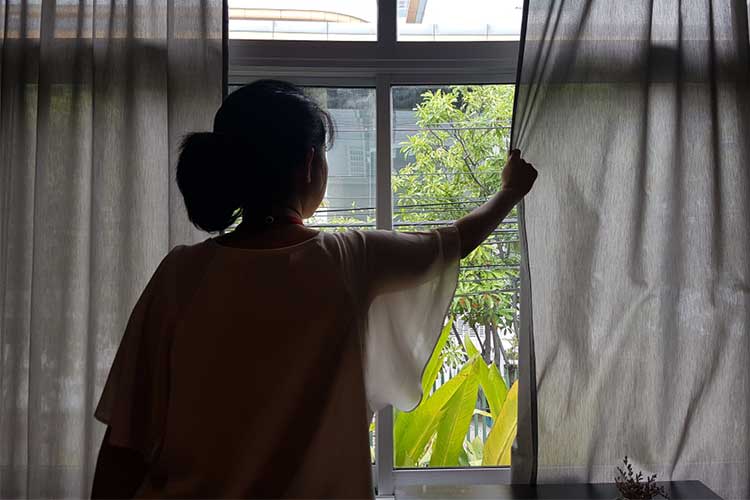 woman closing curtains