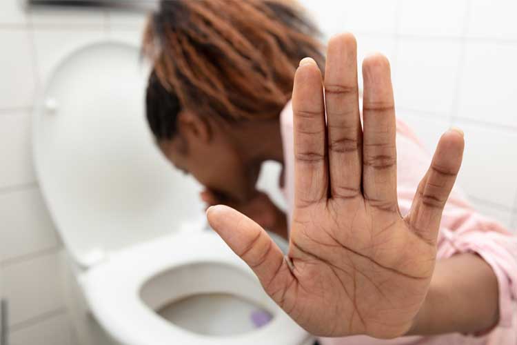 Woman vomting into toilet | Image