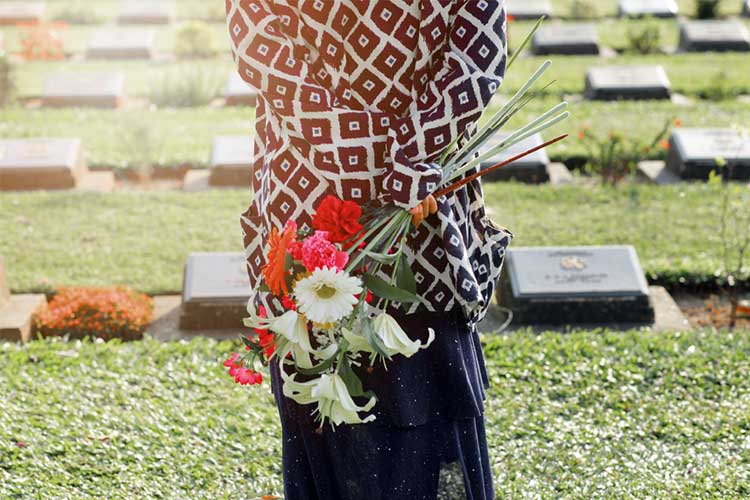 Woman at a cemetary holding flowers