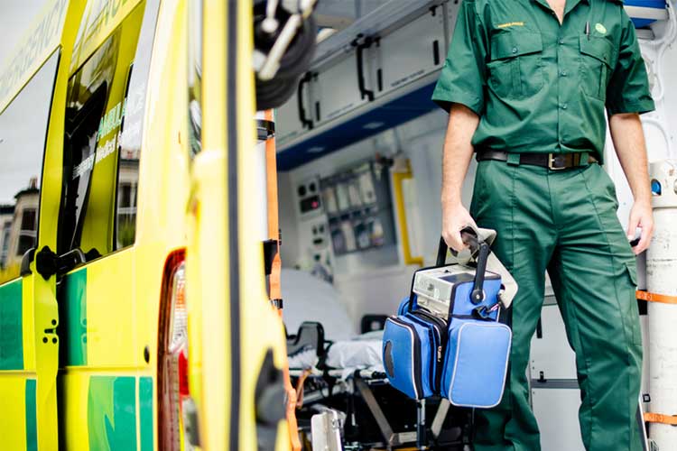 Paramedic standing in front of an emergency vehicle | Image