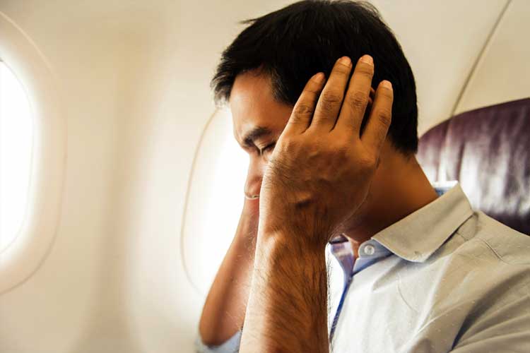 man experiencing earache on plane