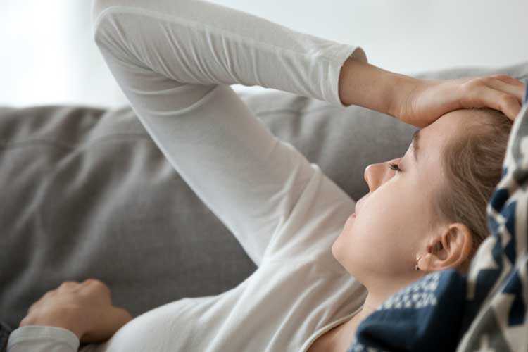 Tired woman laying on a couch | Image