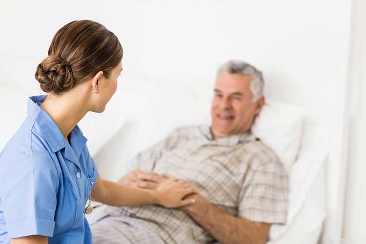 Nurse with elderly man in bed | Image