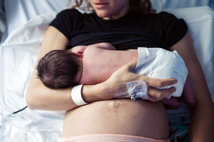 Mother holding her baby in hospital bed