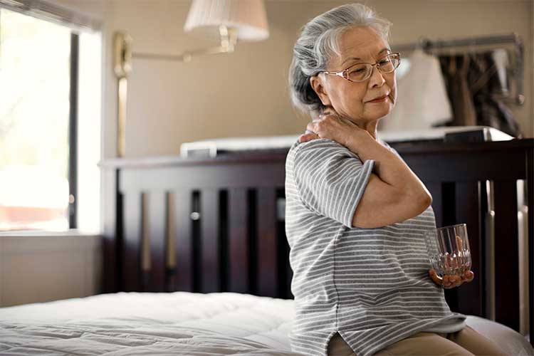 Elderly woman rubbing her neck | Image