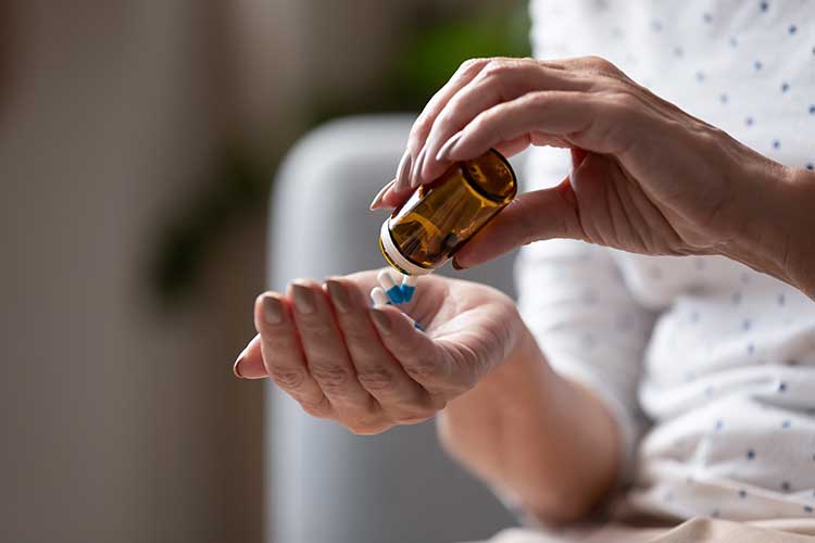 Person pouring pills into their hand | Image