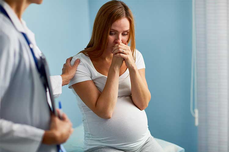 Pregnant woman concerned during consultation | Image