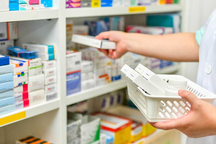 Pharmacist putting products on shelf | Image