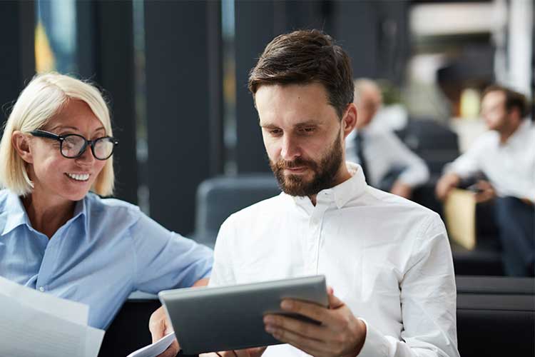 Man showing a woman something on a tablet | Image