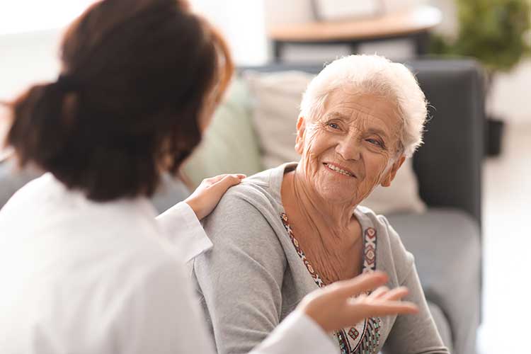 Smiling elderly woman talking with health practitioner | Image