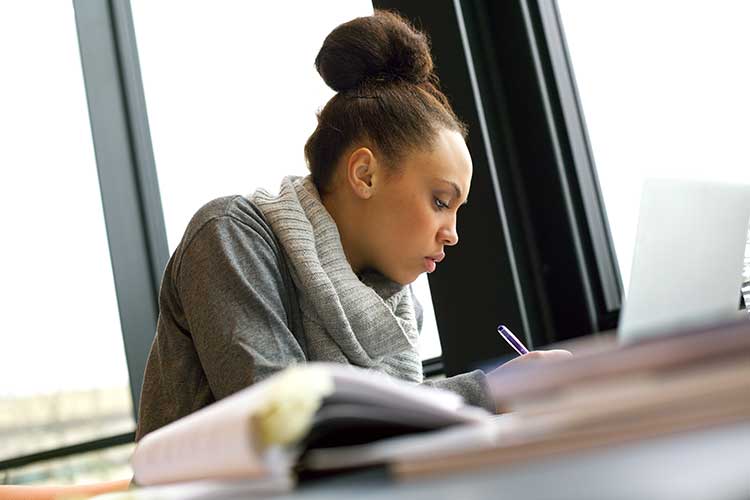 nurse studying with laptop and books