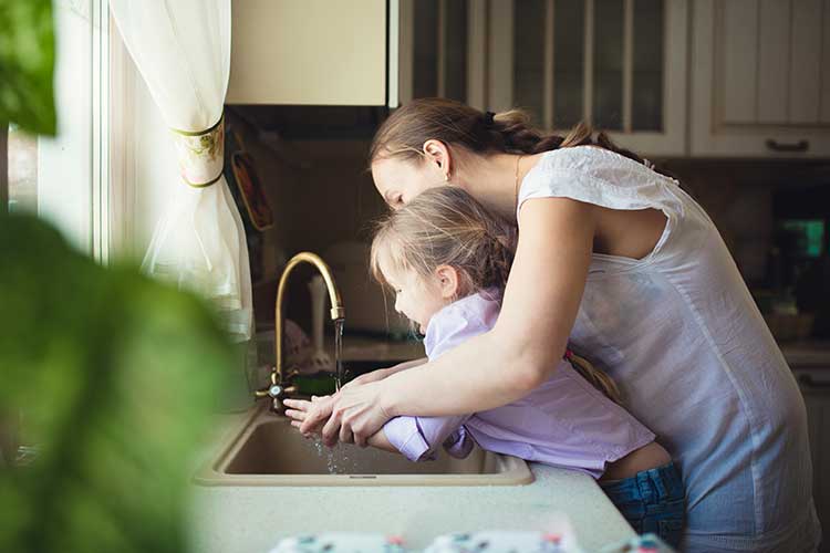mother helping child wash her hands