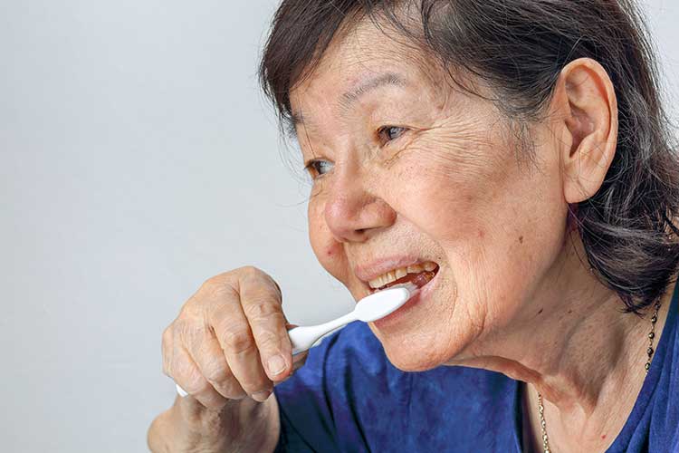 older woman brushing her teeth