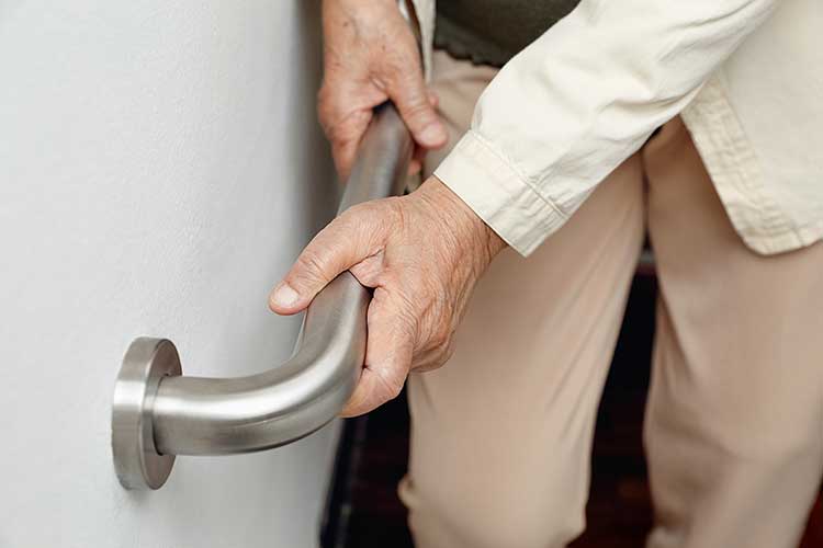 older adult holding handrail