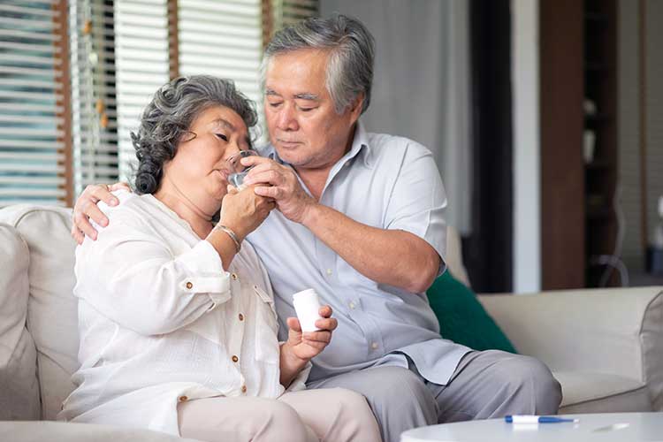 carer helping woman take medicine