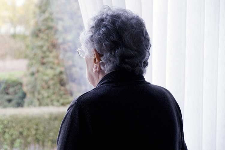 socially isolated woman looking out window