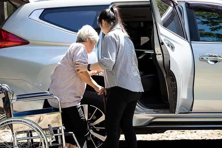 carer helping client get into car